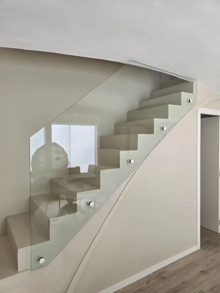 Barandilla de vidrio templado fijada con herrajes puntuales en escalera de obra