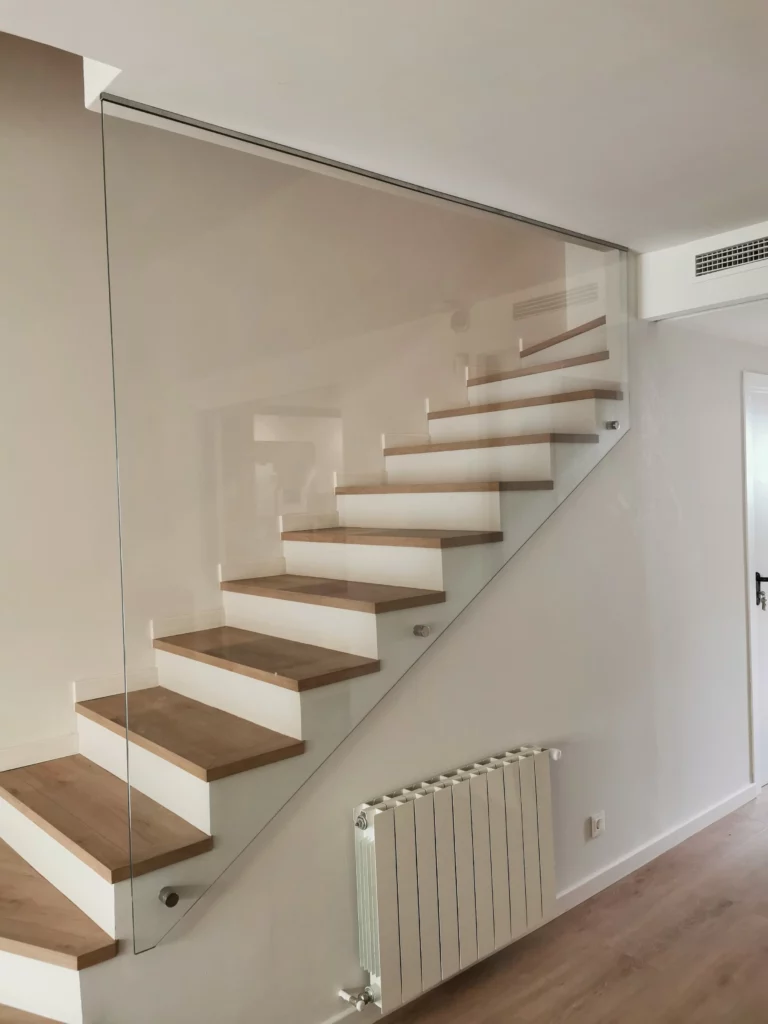 Barandilla de vidrio en escalera con peldaños de madera y estructura ligera